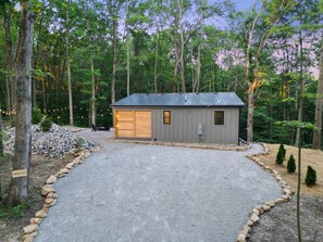 A small, single-story building with a garage, surrounded by a gravel driveway and a stone border. - Cliffside View | Modern Couples Retreat, Hot Tub (Rockbridge)