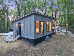 A modern cabin with a stone foundation, large windows, and a deck area.