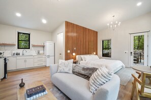 A modern hotel room with a large bed, a sofa, a dining table, and a kitchen area. - Cliffside View | Modern Couples Retreat, Hot Tub (Rockbridge)