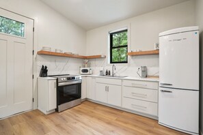 A modern kitchen with white cabinets, a built-in oven, a microwave, a refrigerator, and wooden shelves. - Cliffside View | Modern Couples Retreat, Hot Tub (Rockbridge)