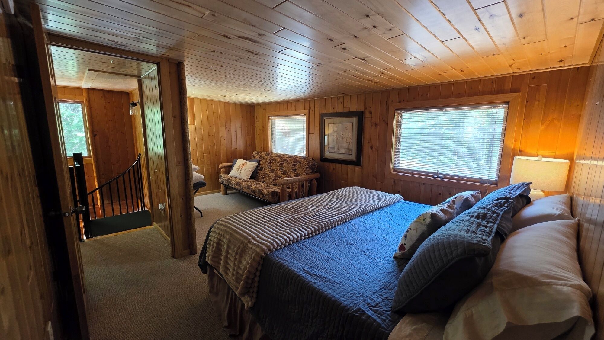 Une chambre dans une cabane en bois, avec un lit, une chaise et une fenêtre.