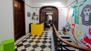 Un couloir avec un sol à carreaux, un comptoir d’accueil et un escalier.