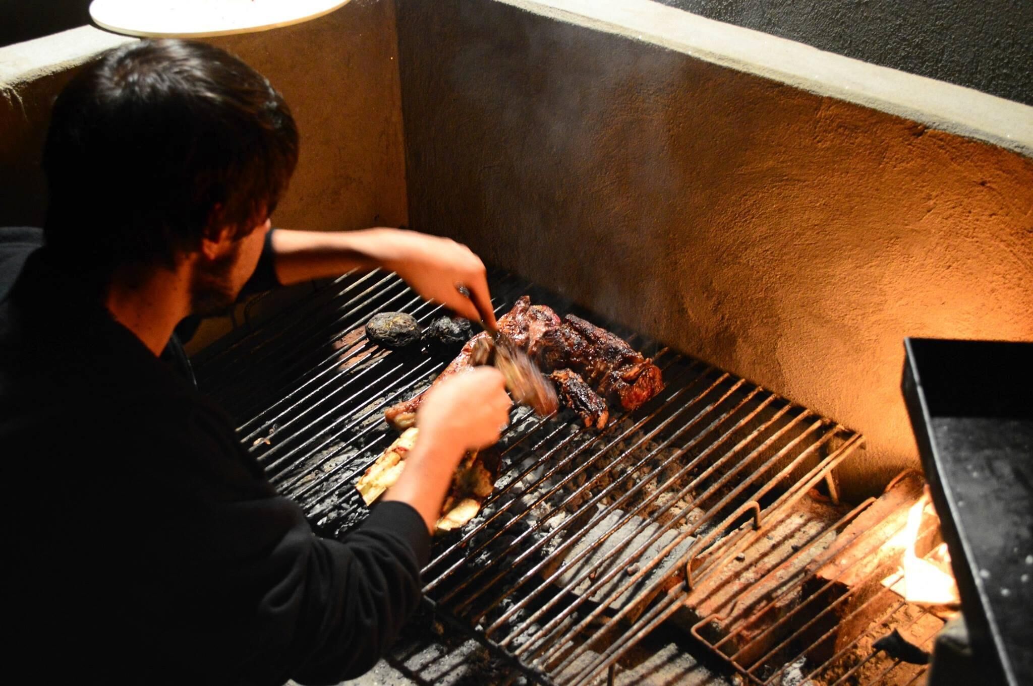 A person grilling meat on a barbecue grill.