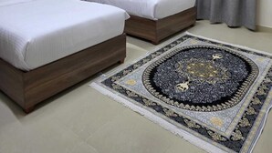 Une chambre d’hôtel avec deux lits, un ventilateur de plafond et un tapis à motifs.