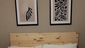A neatly made bed with a wooden headboard, two pillows, and two folded towels on the bed.