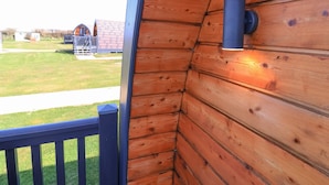 Eine Holzfassade mit einem blauen Geländer und einem blauen, zylindrischen Objekt, vermutlich einer Lampe, die daran befestigt ist.