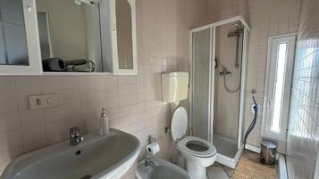Et badeværelse med vask, toilet og bruser.