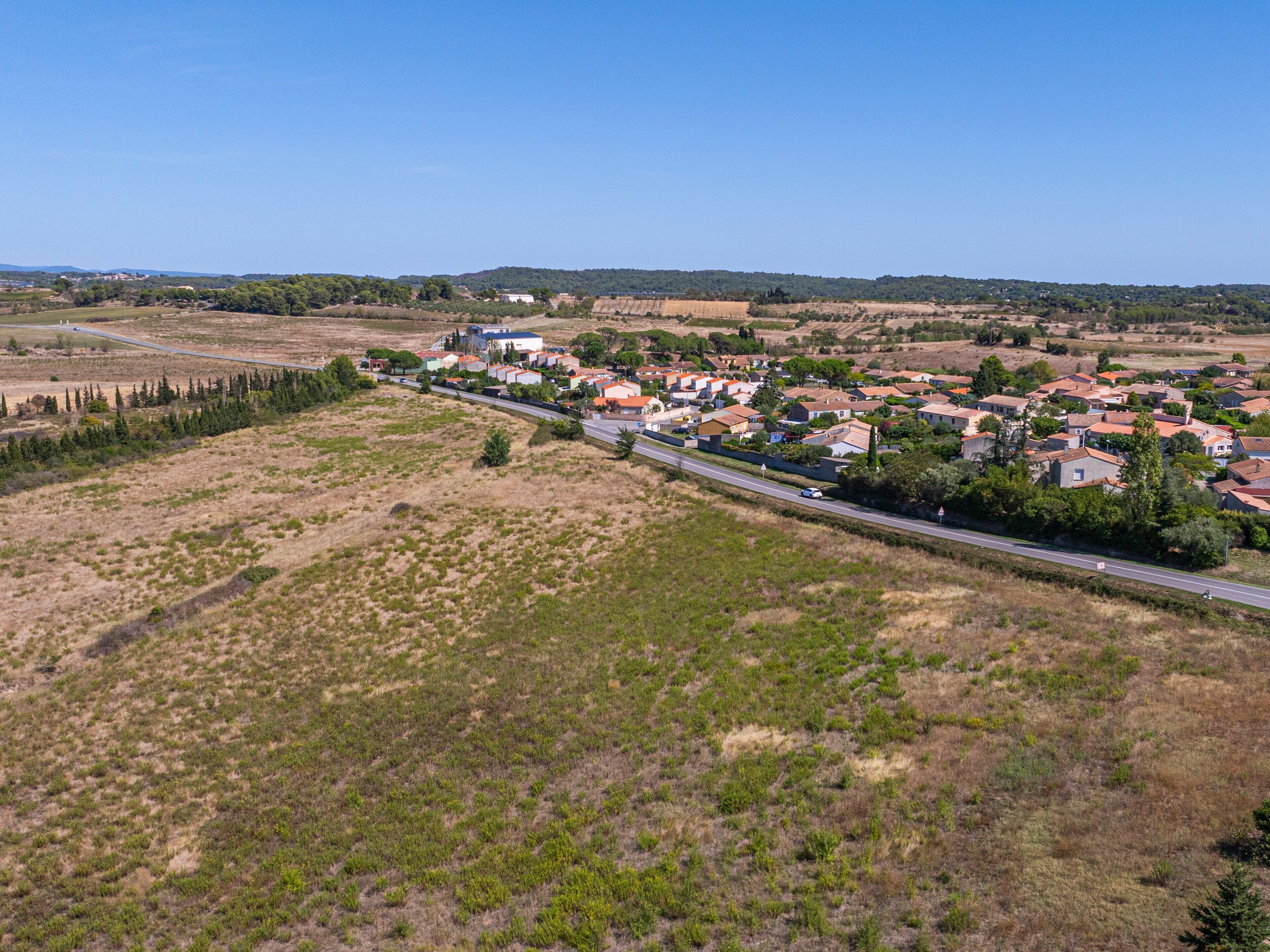 Vista aérea de un pueblo pequeño con casas, una calle principal y campos circundantes.
