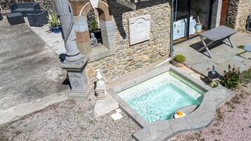 A stone building with a swimming pool, outdoor seating, and a stone wall.