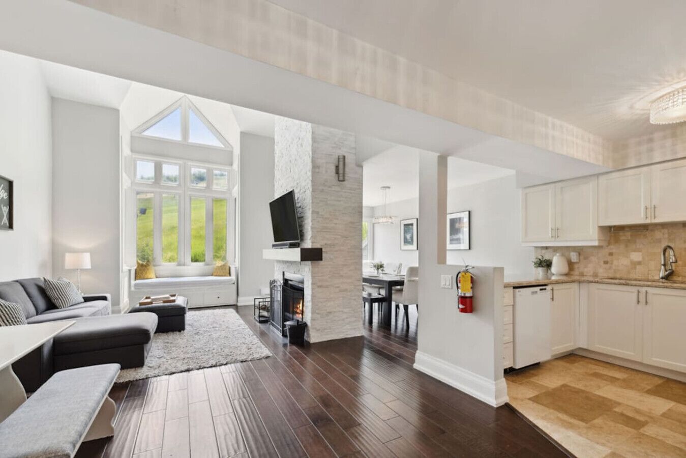 A spacious living area with a fireplace, a dining area, and a kitchen with white cabinets.