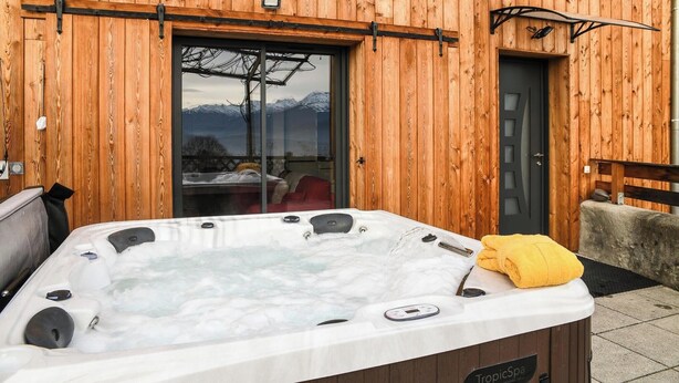 A wooden spa tub with a yellow towel, a glass door, and a mountain view. - Chalet 'Au Pied De L'arcluse' with Mountain Views, Wi-Fi, and Air Conditioning (Saint-Pierre-d'Albigny)