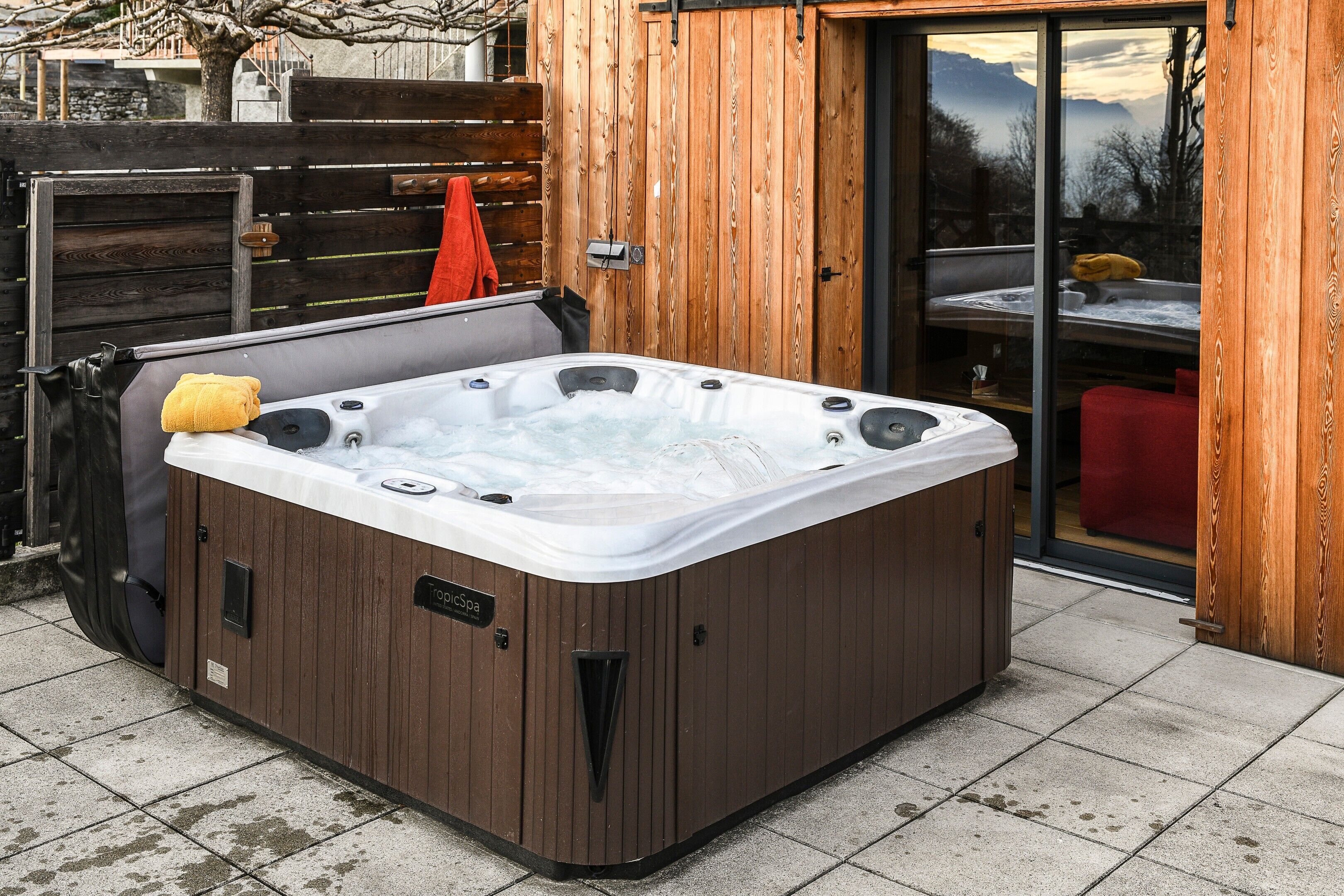 A hot tub in a wooden cabin with a sliding glass door.
