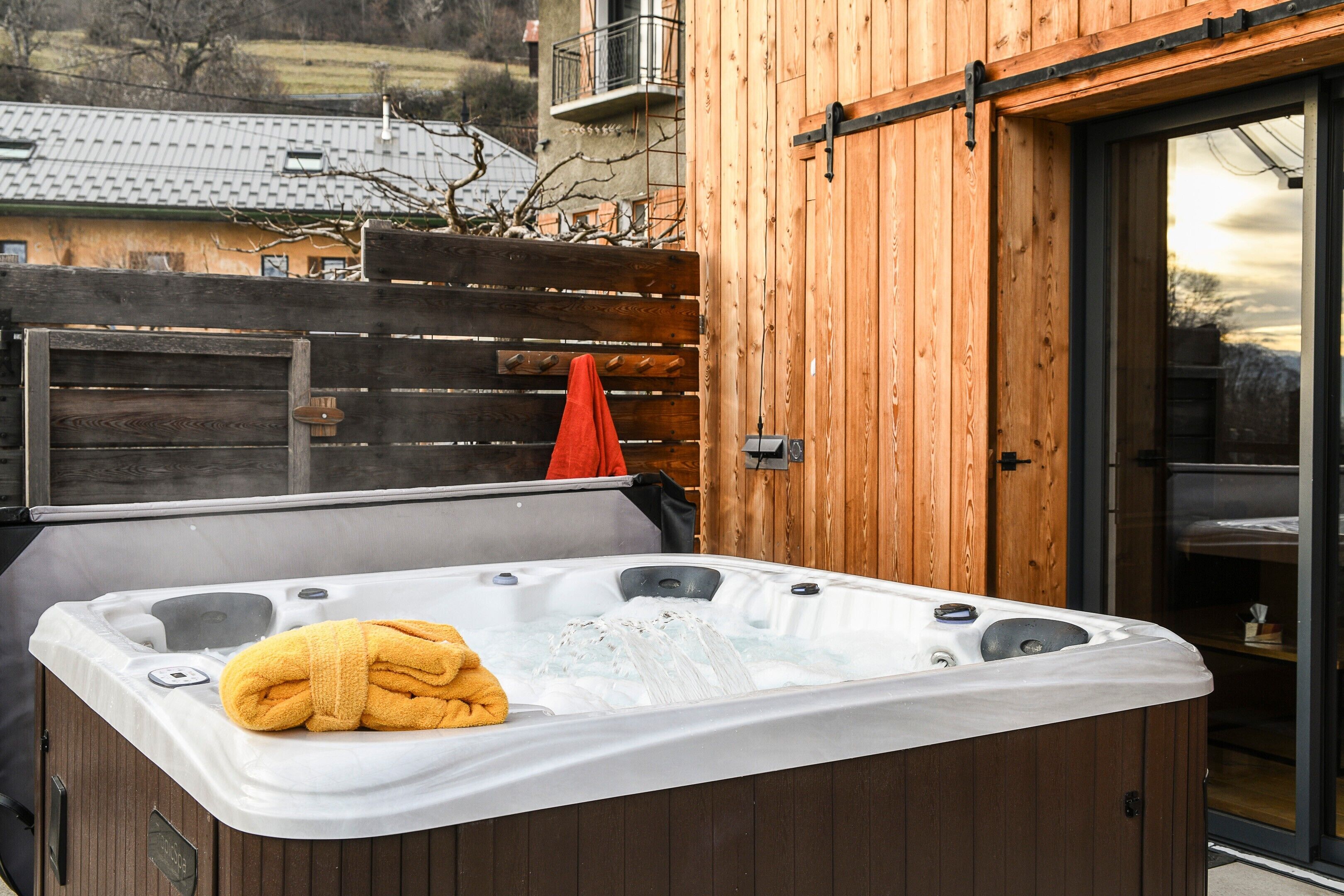 Un jacuzzi con una toalla, revestimiento de madera y puerta corrediza de vidrio.