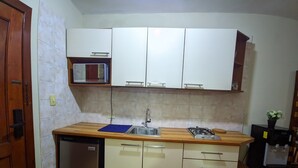 Une cuisine de taille réduite équipée d’un lave-vaisselle, d’un évier, d’une cuisinière et de placards.