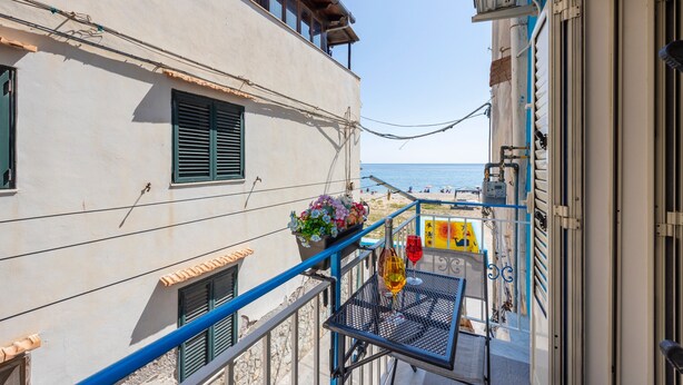 Ein Balkon mit Tisch, Topfpflanze und Meerblick.