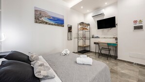 Ein Hotelzimmer mit Bett, Schreibtisch, Sessel, Fernseher und einem Bild an der Wand.