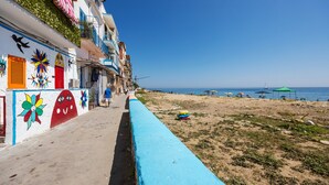 Eine Küstenstraße mit bunten Häusern, einem Strand und Sonnenschirmen.