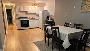 A modern kitchen with white cabinets, a dining table set for four, and a chandelier. - Incredible NYC and Water Views 3 bedrooms only 15 min from NYC New Floors  (West New York)
