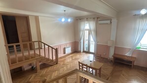 A spacious room with a wooden herringbone floor, a staircase, a dining table, and a bench.
