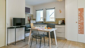 A compact kitchen with a dining area, a TV, and a microwave. - Chez Flo Apartment – Cozy Studio with Mountain View and Air Conditioning (Saint-Pierre-d'Albigny)