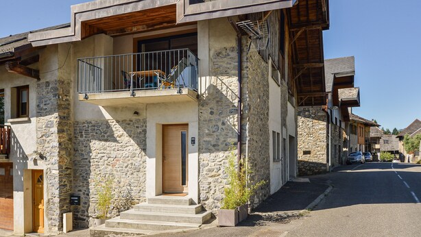 A stone building with a wooden door, a balcony, and a staircase leading to the entrance. - Chez Flo Apartment – Cozy Studio with Mountain View and Air Conditioning (Saint-Pierre-d'Albigny)