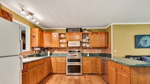 A kitchen with wooden cabinets, a microwave, an oven, and a sign that reads "Gathering Place".