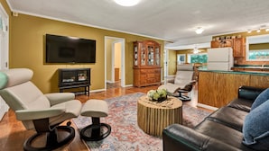 A living room with a sofa, armchair, ottoman, and a television.
