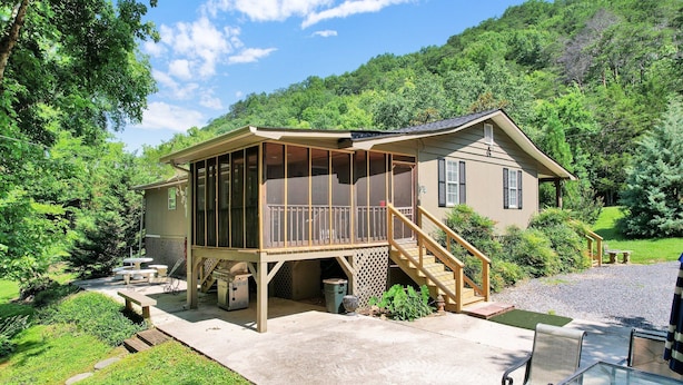 A house with a covered porch, outdoor seating, and a staircase leading to a deck.