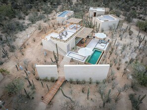 A desert resort with multiple buildings, a swimming pool, and a wooden deck.