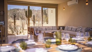 Un comedor con vistas a cactus y montañas desérticas, un sofá y un ventilador de techo.