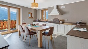 A modern kitchen with a dining area, large windows, and a view of mountains. - Apartment 'Marmotta' with Mountain View, Shared Garden and Wi-Fi (Oga)
