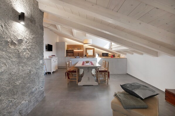 En modern loftlägenhet med matplats, kök och en vägg av sten.