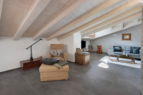 A spacious loft with a high ceiling, a sofa, a chair, and a small table with a decorative item.