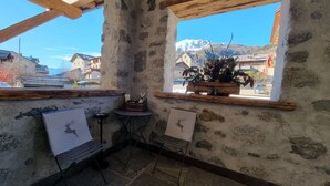 A rustic interior with a stone wall, wooden beams, a window with a plant, and two framed pictures. - Apartment 'Scoiattolo' with Mountain View, Shared Garden and Wi-Fi (Oga)