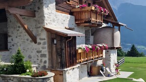 A chalet with a stone facade, wooden balconies, and a view of mountains. - Apartment 'Scoiattolo' with Mountain View, Shared Garden and Wi-Fi (Oga)
