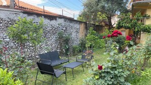 A patio with a stone wall, a metal table, two chairs, and potted plants. - Hysa guest house (Shkodër)