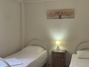 A bedroom with two single beds, a bedside table with a lamp, and a wall-mounted painting. - Hysa guest house (Shkodër)