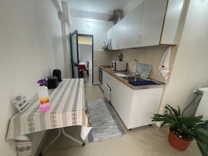 Una cocina compacta con comedor, microondas, tostadora y lavamanos.