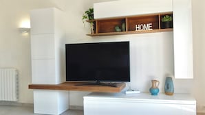 Un saló modern amb un televisor de pantalla plana fixat en una estant de fusta sobre una taula de consola blanca.