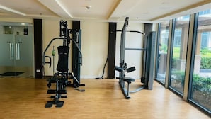 A gym with exercise equipment, large windows, and a wooden floor.
