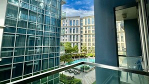 A modern building with a glass facade, a rooftop pool, and a well-maintained garden area.