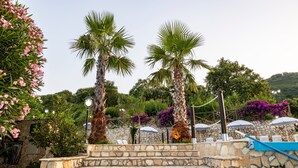 Stone steps leading to a pool area with palm trees and outdoor seating. - 'Arcaloro Resort Infinito' Room with Mountain View and Hot Tub (Sant'Angelo di Brolo)