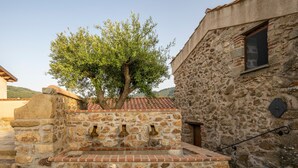 A stone building with a tree in front, a window, and a stone wall with a brick base. - Room 'Luna' with Mountain View, Wi-Fi and Air Conditioning (Sant'Angelo di Brolo)