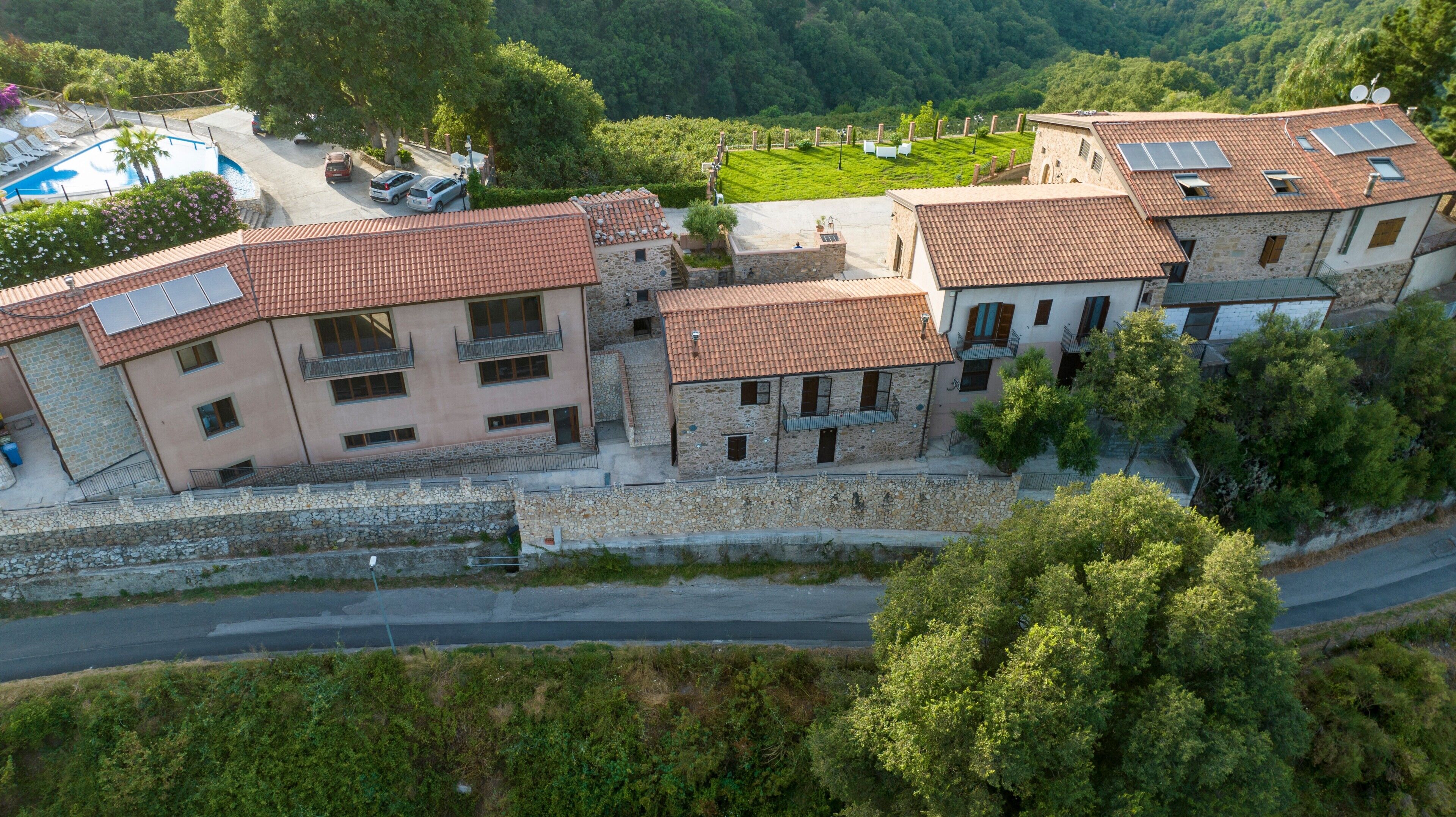 A multi-story building with stone walls, red-tiled roofs, and balconies.