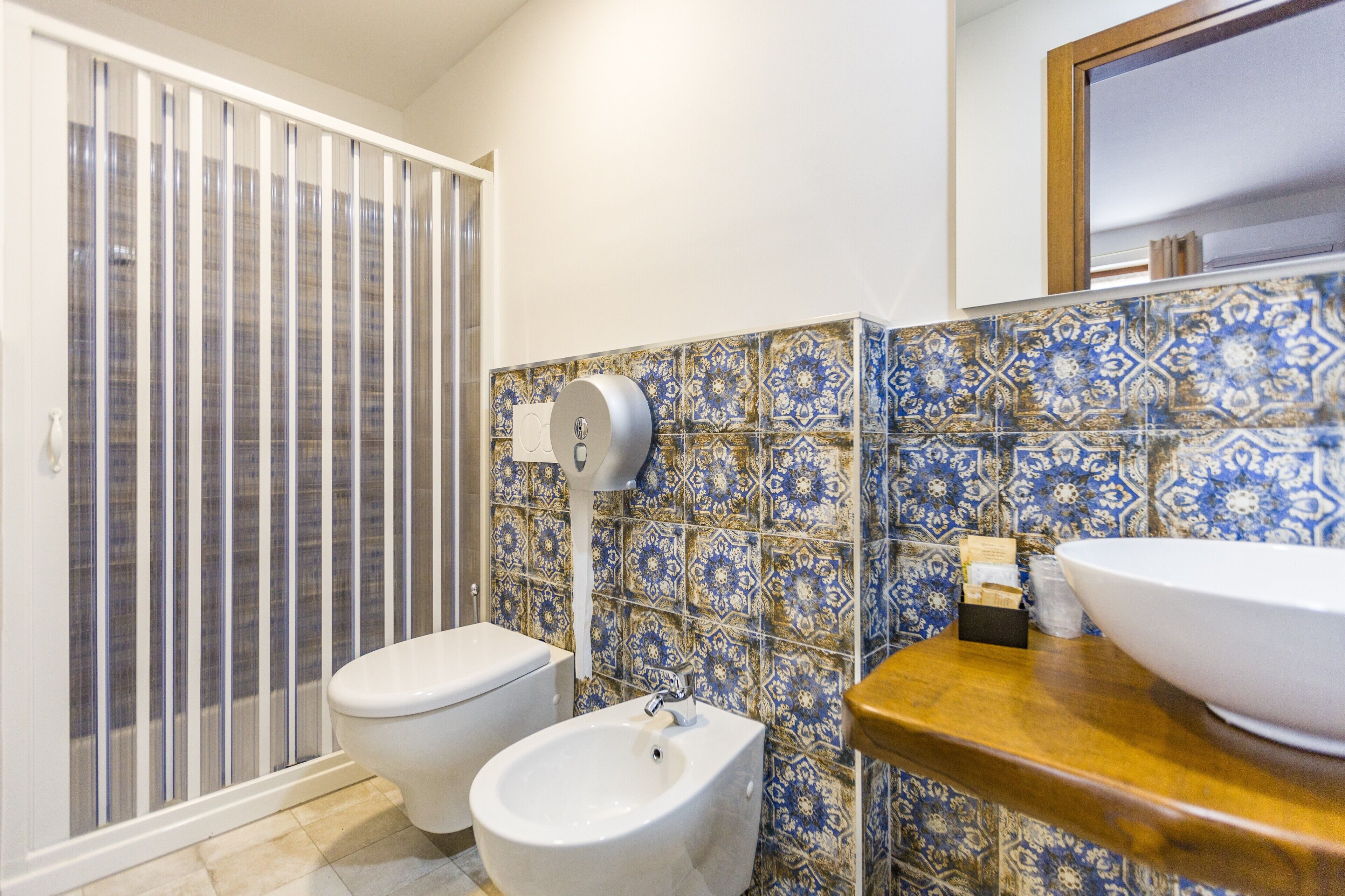 A bathroom with a toilet, bidet, and a sink with a mirror above it.