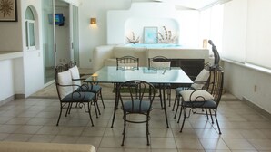Un espace repas avec une table en verre entourée de chaises, d’un canapé et d’une cheminée.