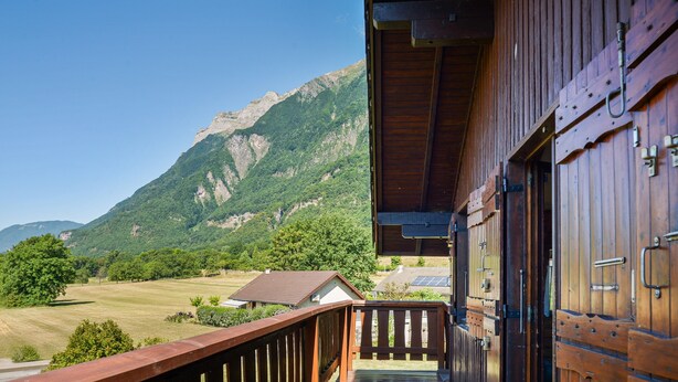 Un balcón de madera con vista a un paisaje montañoso.