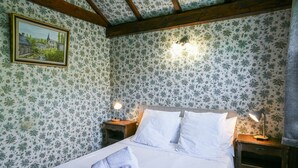 Una cama bien hecha con sábanas blancas, dos lámparas de noche y un cuadro en la pared.