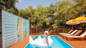 A swimming pool with a swan float, lounge chairs, and a wooden deck. - Pool, Firepit, Mins to DT, SXSW, ACL, Sleeps 6 (Austin)