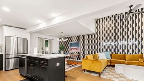 A modern kitchen with stainless steel appliances, a dining area with a yellow sofa, and a patterned wall. - Pool, Firepit, Mins to DT, SXSW, ACL, Sleeps 6 (Austin)